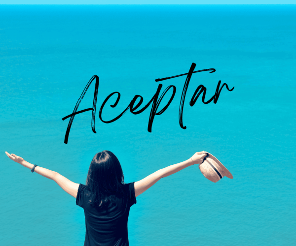 Mujer con los brazos abiertos frente al mar, representando la aceptación interior como parte del proceso de transformación personal